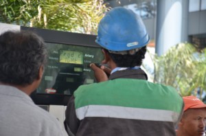 Des techniciens en train de changer les prix à la pompe.